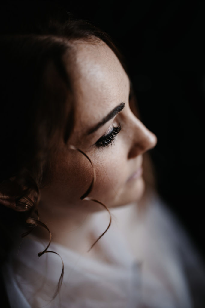 Braut im close up mit glamourösem Augen Make-Up und Locken in der Vorderpartie.
